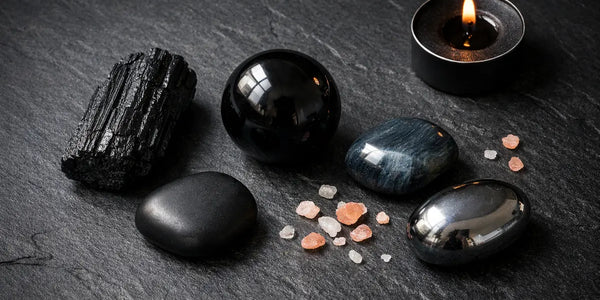 collection de pierres noires en lithothérapie tourmaline obsidienne onyx oeil de faucon sur fond sombre