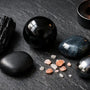collection de pierres noires en lithothérapie tourmaline obsidienne onyx oeil de faucon sur fond sombre