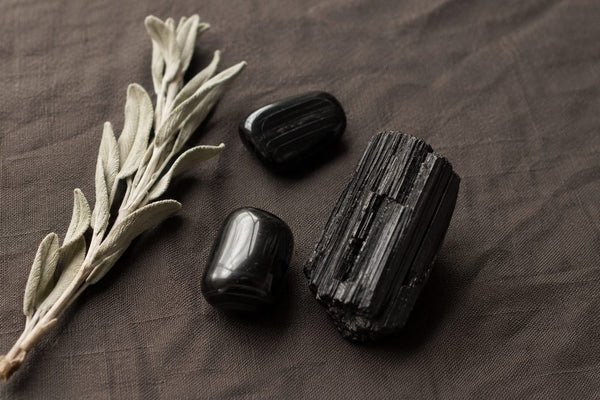 tourmaline noire brute et polie sur tissu naturel, pierre de protection et d'ancrage en lithothérapie